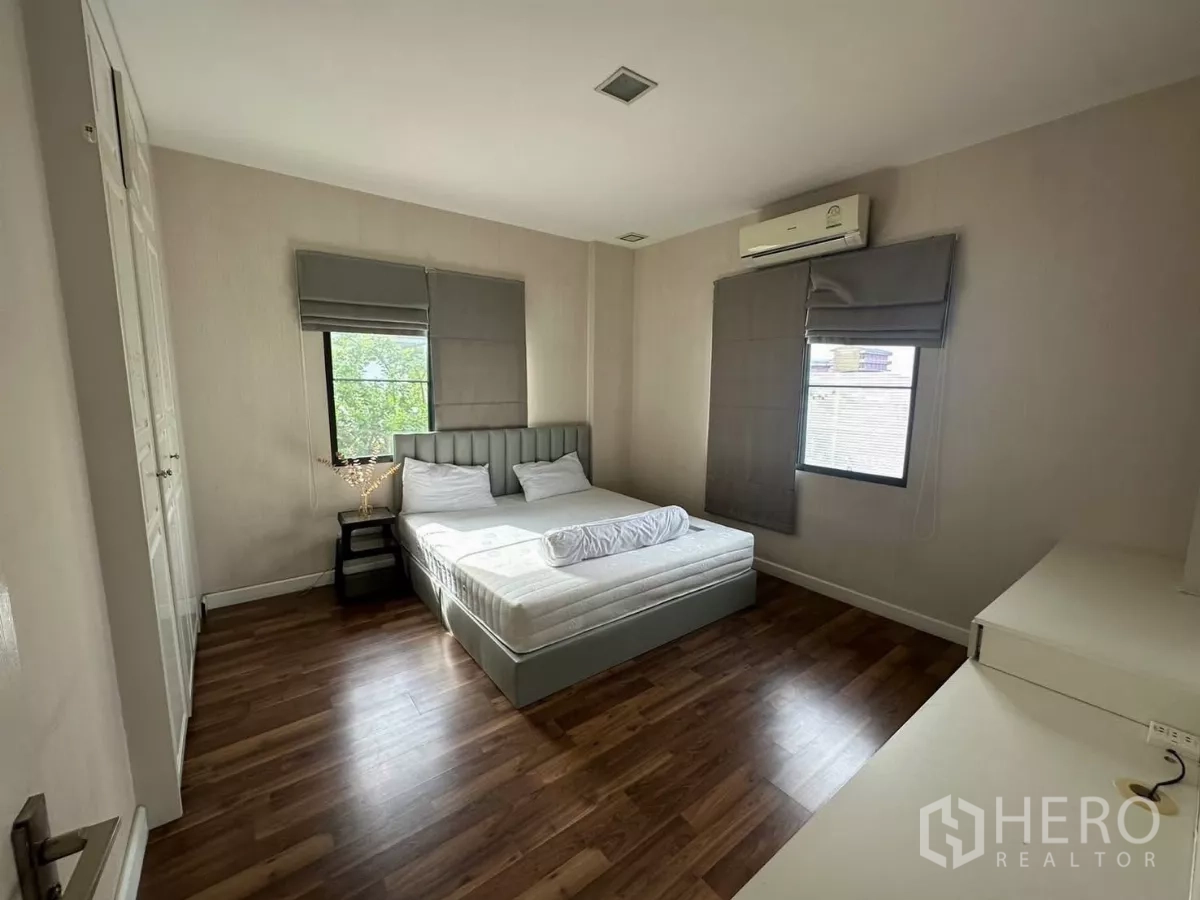 Detached House for rent or sale in Bang Kapi, Bangkok - Guest bedroom with bed, two windows, wood floors and air conditioning.