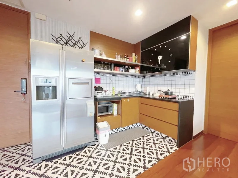 Condominium for sale in Khlong Toei, Bangkok - Compact L-shaped kitchen with stainless double-door fridge, open shelving and patterned floor tiles.