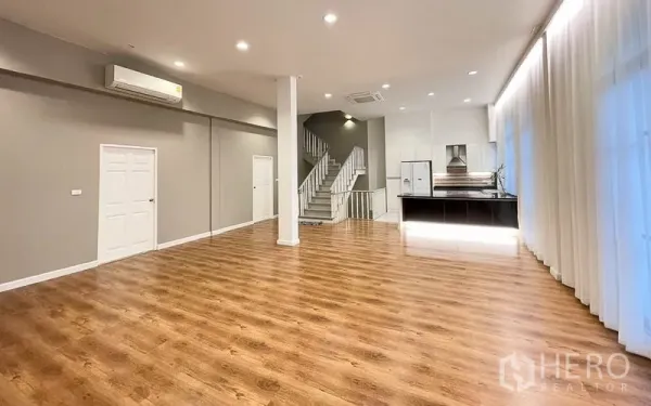 Townhouse for rent in Yan Nawa, Bangkok - Spacious living room with timber flooring, high ceiling, air conditioning and staircase to upper levels.
