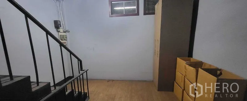 Shophouse for rent in Khlong Toei, Bangkok - Landing area beside staircase with small window and storage boxes.