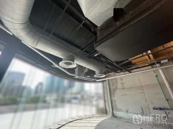 Retail Space for rent in Pathum Wan, Bangkok - Curved glass shopfront with visible metal air ducts and city view through the windows.