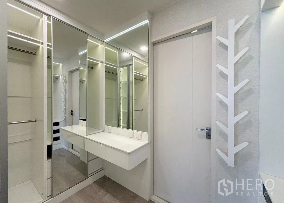 Detached House for rent or sale in Prawet, Bangkok - Master walk-in closet with mirrored wardrobes and dressing vanity under bright lighting.