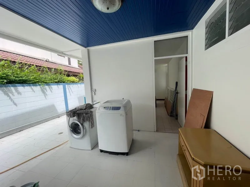 Detached House for rent in Khlong Toei, Bangkok - Covered utility and laundry area with washing machines and blue ceiling.