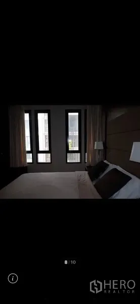 Condominium for rent in Watthana, Bangkok - Bedroom with large vertical windows, curtains and an upholstered headboard for natural light and privacy.