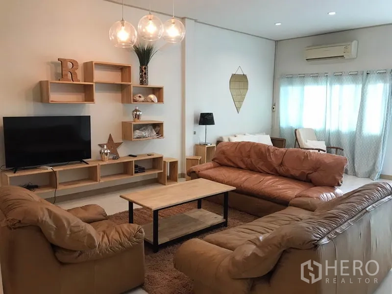 Townhouse for rent or sale in Phra Khanong, Bangkok - Bright lounge with large windows, leather sofas, TV unit and air conditioning.