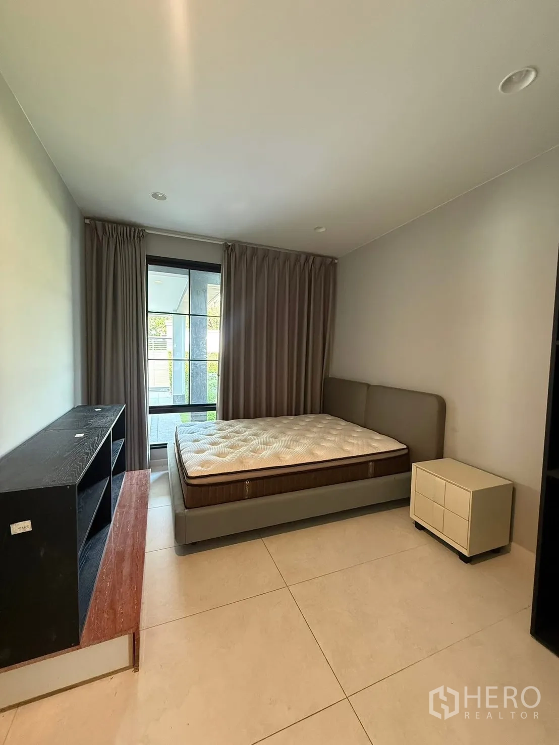 独栋房屋 for rent in Bang Kapi, Bangkok - 客卧设瓷砖地面、双人床与床头柜，带推拉窗。