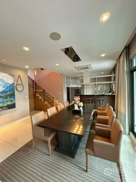 Detached House for sale in Bang Lamung, Chon Buri - Formal dining with pendant lighting beside a pantry bar and sliding glass doors.