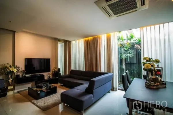 联排别墅 出租或出售在Watthana, Bangkok - 客厅电视墙，玻璃门连接绿植庭院与餐桌