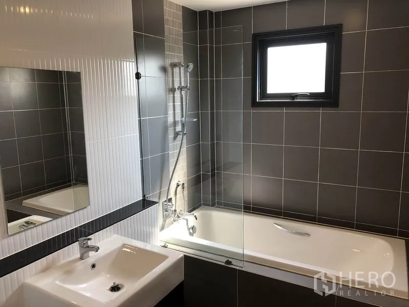 Detached House for rent in Prawet, Bangkok - Contemporary bathroom with bathtub, shower fixture, small window and sink.