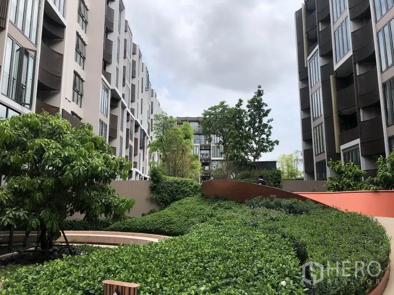 Condominium for sale in Watthana, Bangkok - Landscaped courtyard between low-rise condo buildings with greenery and pathways.