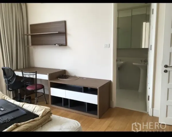 公寓 出租在Khlong Toei, Bangkok - 带书桌、椅子、壁架和电视柜的工作区，旁边连通明亮浴室。