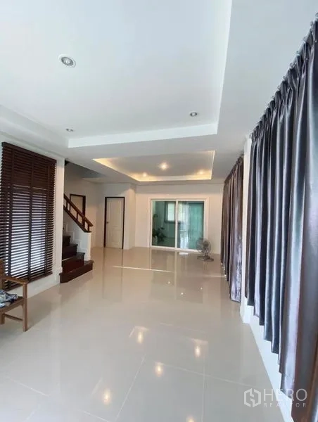 Detached House for sale in Bang Phli, Samut Prakan - Spacious living room with glossy floors, recessed ceiling lights, and large curtained windows.