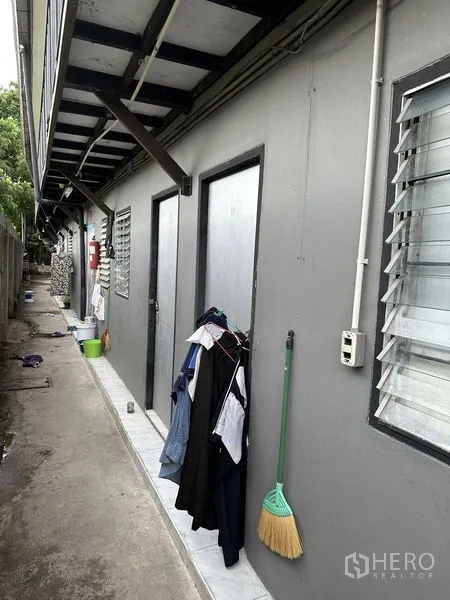 Factory for rent in Bang Bua Thong, Nonthaburi - Exterior staff quarters and utility rooms along a narrow walkway.