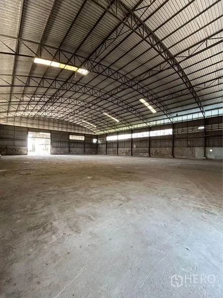 货栈 出租在Sam Phran, Nakhon Pathom - 仓库内部空间开阔，高弧形钢梁屋顶，采光带与混凝土地面。