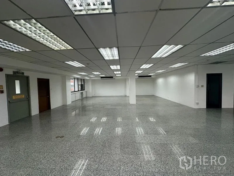 办公空间 出租 - 明亮办公区，设紧急出口门、多扇窗与网格吊顶灯。