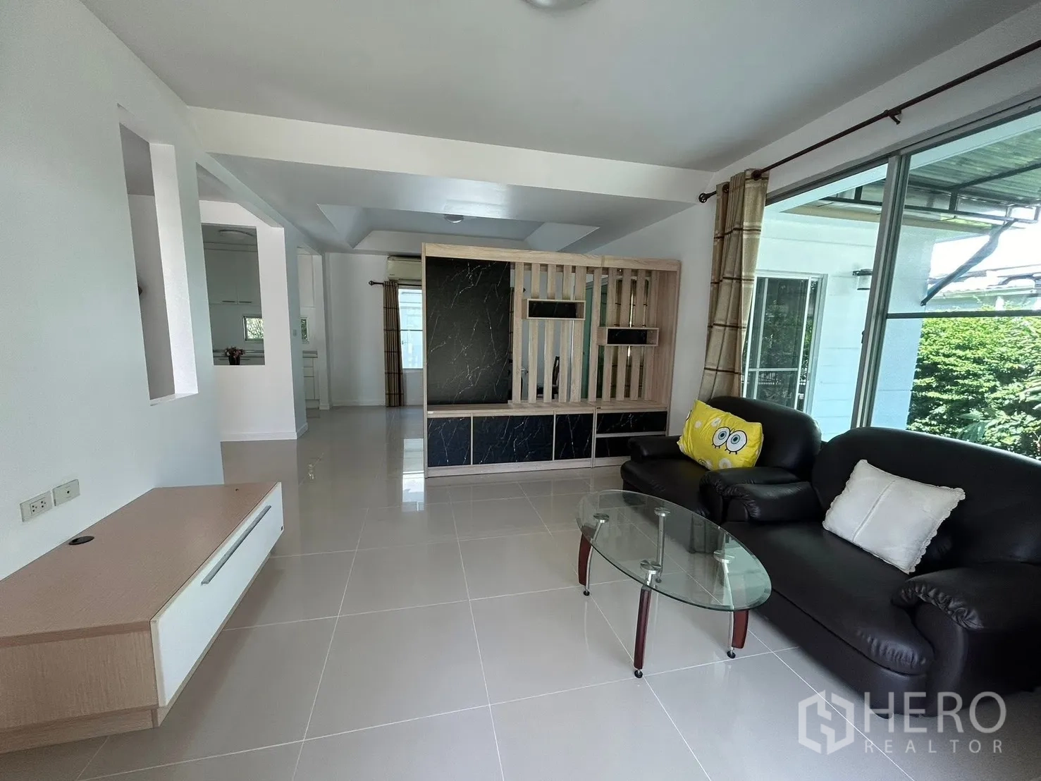 Detached House for rent in Bang Na, Bangkok - Open-plan living room with leather sofas, glass coffee table, and large windows.