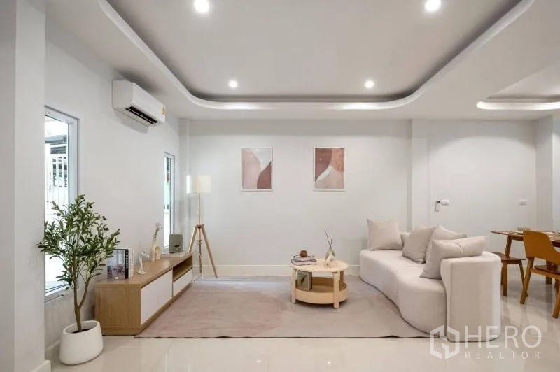 Townhouse for sale in Khlong Toei, Bangkok - Wide view of the living room with recessed ceilings, sofa, TV console and open dining.