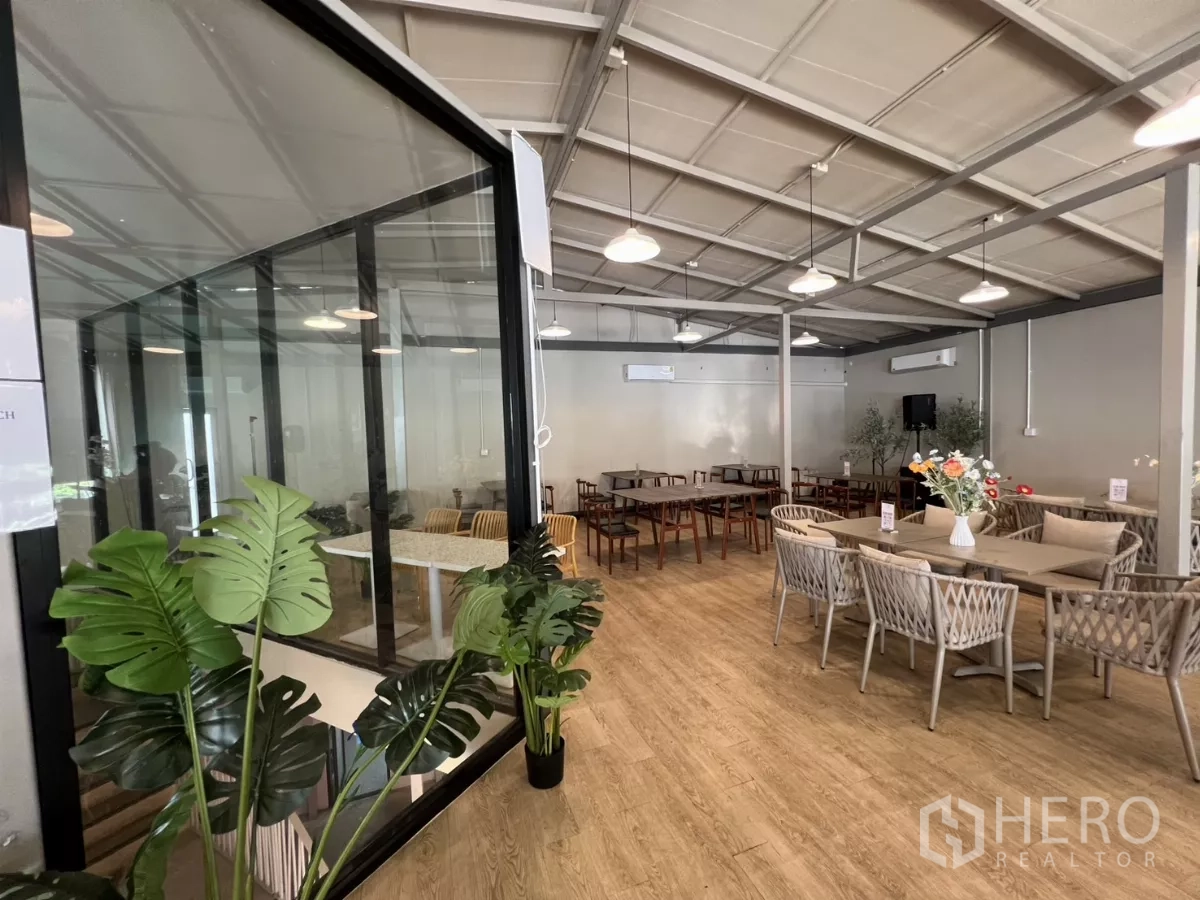 零售空间 出租在Khlong Toei, Bangkok - 宽敞咖啡馆风室内，设玻璃会议室、吊灯、绿植与编织座椅。