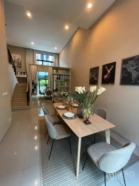 Townhouse for rent or sale in Suan Luang, Bangkok - Open-plan dining area with a high ceiling, staircase, glass partition and abundant natural light.