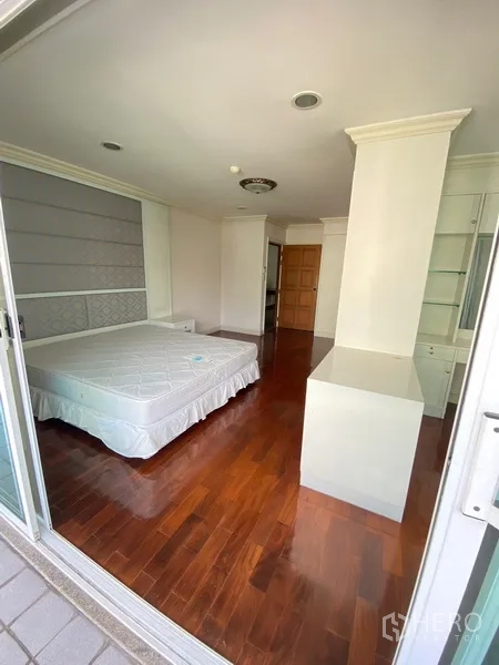 房间 出租在Watthana, Bangkok - 卧室直通阳台，内置置物架与亮泽木地板。
