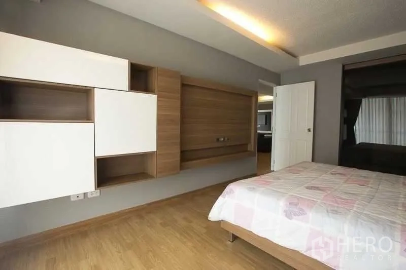 Condominium for rent in Khlong Toei, Bangkok - Master bedroom alternate view showing built-in storage and TV feature wall.
