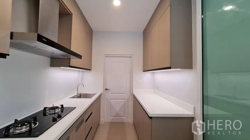 Detached House for rent in Samut Prakan - Full view of the galley kitchen with dual counters and a door at the end.