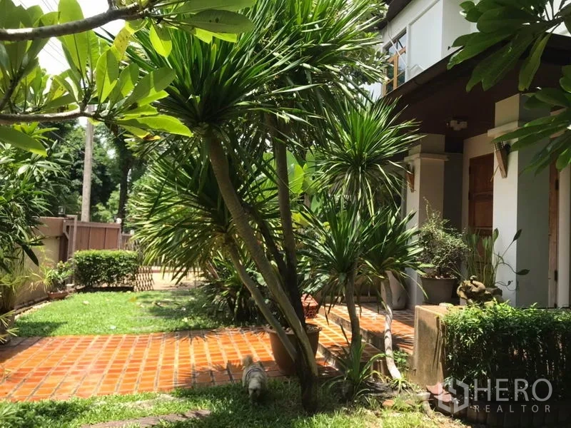 独立式住宅 出售在Lat Phrao, Bangkok - 前庭花园与铺砖步道，热带植物环绕及有顶门廊。