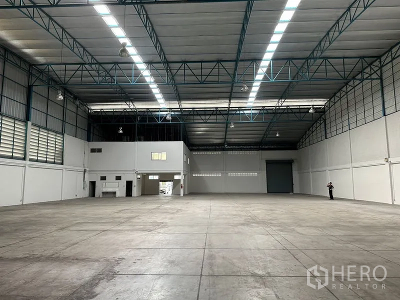 โรงงาน ให้เช่าในSi Racha, Chon Buri - มองไปยังภายในโกดังที่มีประตูม้วนโหลดสินค้าและบล็อกออฟฟิศด้านข้าง พื้นคอนกรีตกว้าง
