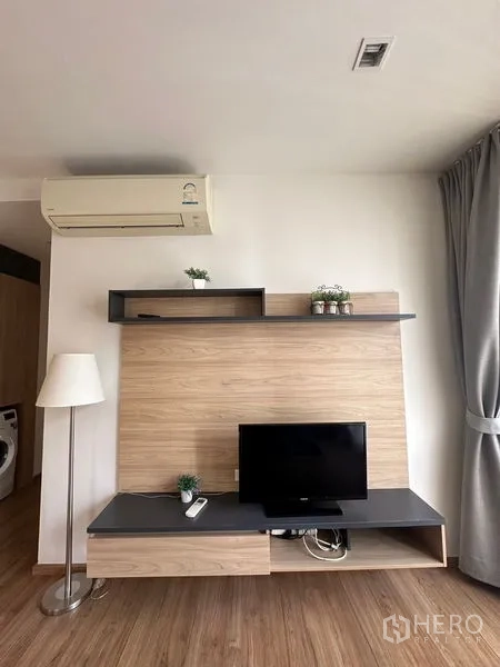 Condominium for rent in Watthana, Bangkok - Close-up of built-in TV wall with shelves and floor lamp.