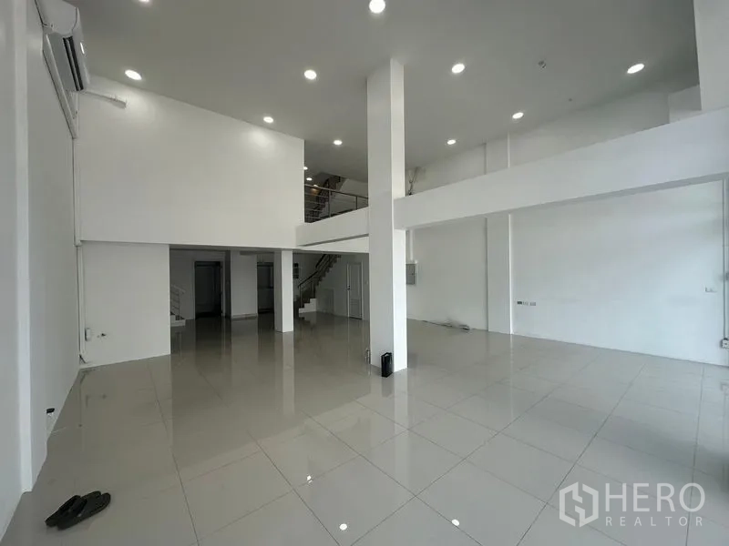 Home Office for rent in Bang Na, Bangkok - Double-height lobby with columns, mezzanine level, staircase and polished flooring.