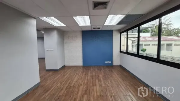 办公空间 出租在Watthana, Bangkok - 开放工位区，蓝色强调墙、LED照明与侧窗。