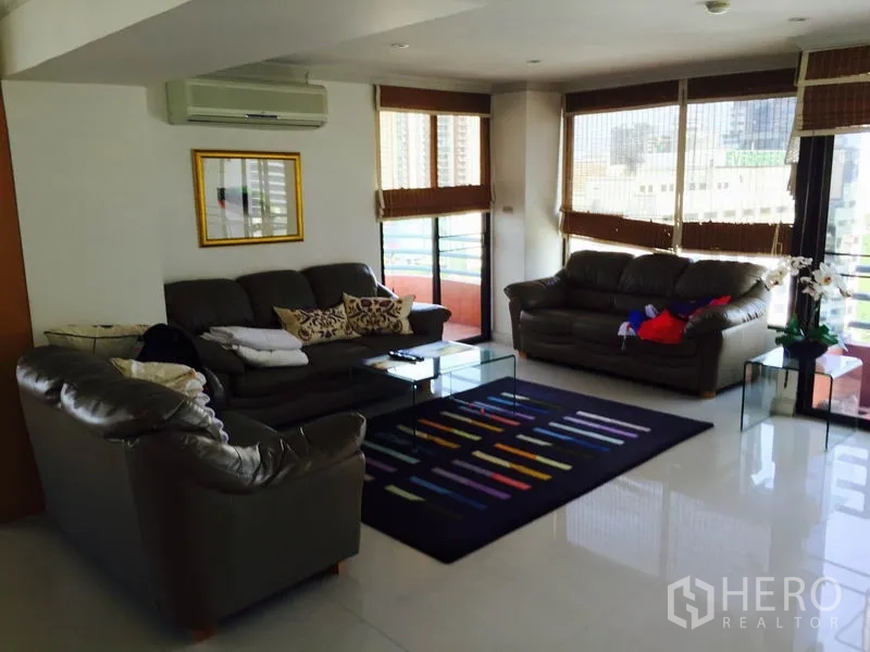 Condominium for rent in Bang Rak, Bangkok - Bright corner lounge with leather sofas, wide windows, balcony and city views.