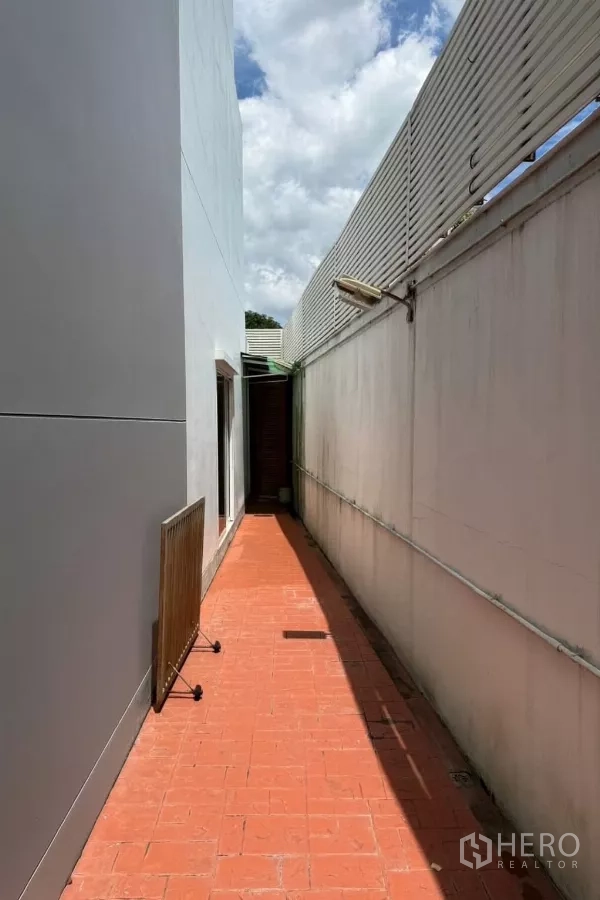 บ้าน ขาย - ทางเดินบริการด้านข้าง พื้นกระเบื้องสีอิฐและผนังบังสายตา