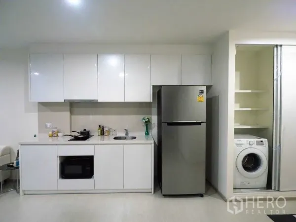 公寓 出租在Khlong Toei, Bangkok - 白色一字型厨房，储物柜、冰箱与带洗衣机的柜体