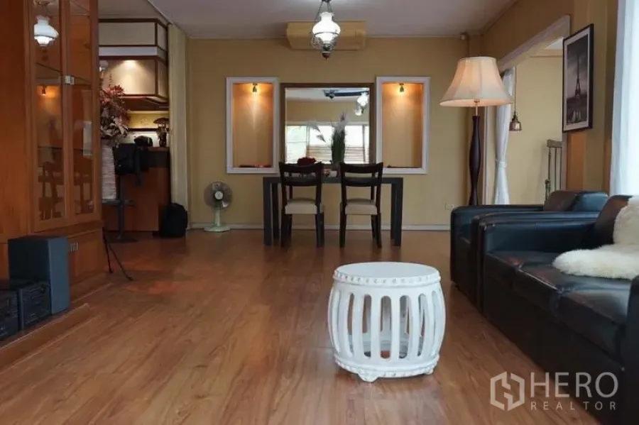 Detached House for rent in Suan Luang, Bangkok - Open-plan lounge and dining area with wooden floor, pendant lights and a black dining set.