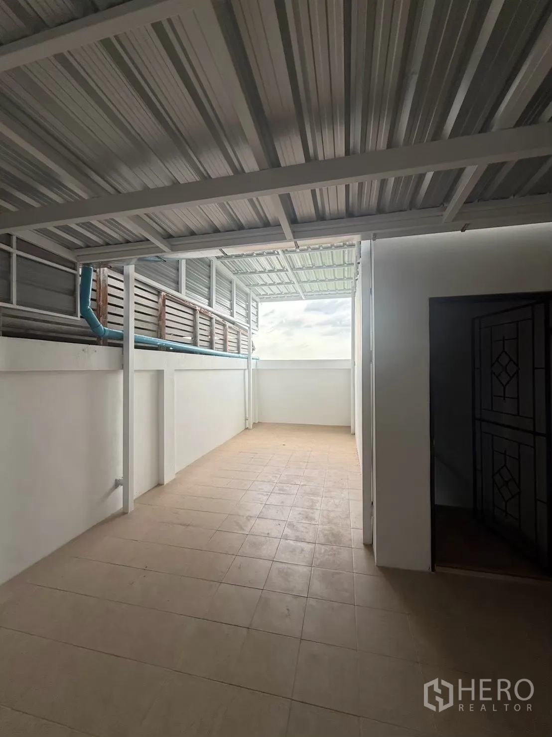 Shophouse for rent in Pak Kret, Nonthaburi - Semi-open covered area with roof panels and daylight at the end.