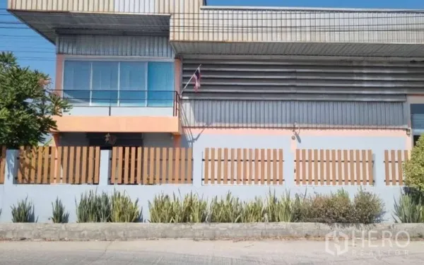 货栈 出售在Pathum Thani - 建筑正立面，带办公室玻璃窗与阳台，外有围栏。