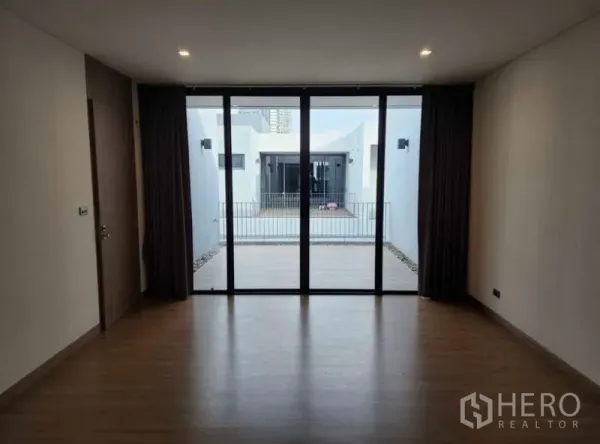 Townhouse for sale in Yan Nawa, Bangkok - Bedroom facing a private terrace through wide sliding glass doors with courtyard view.