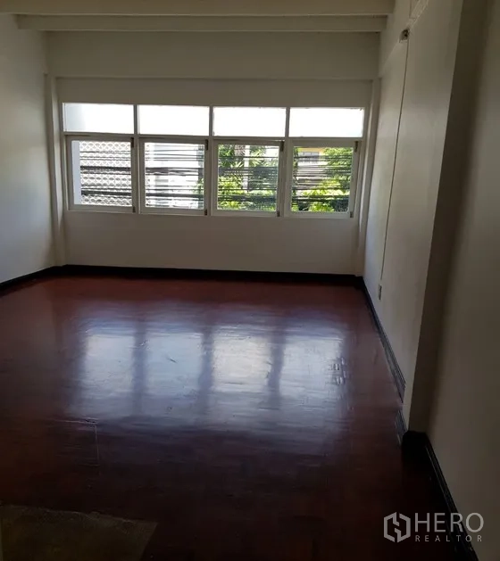 Shophouse for rent in Watthana, Bangkok - Upper-floor room with large windows and polished wooden floor.