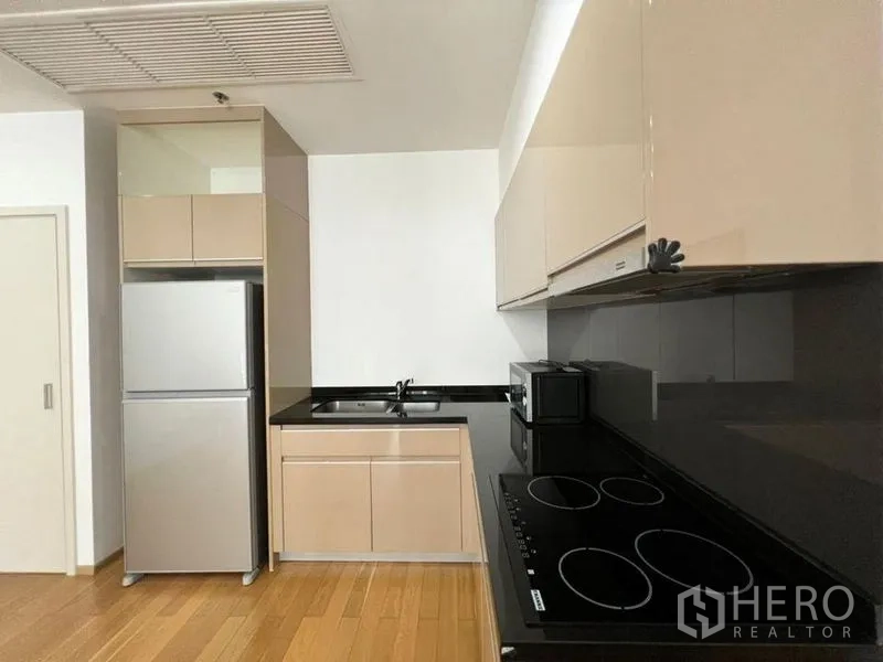 公寓 出租在Khlong Toei, Bangkok - 现代厨房，黑色台面，电炉、微波炉与双门冰箱齐全。