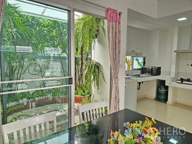 带办公室的家 出租或出售在Suan Luang, Bangkok - 餐区临近推拉门，可见厨房与小花园