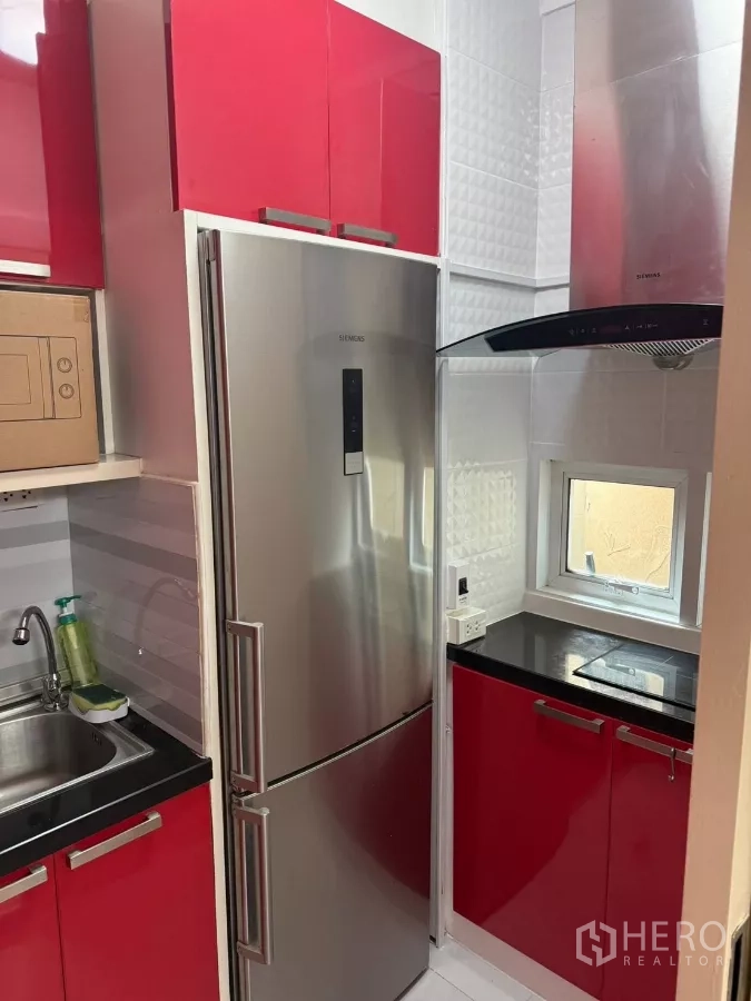 Townhouse for rent in Suan Luang, Bangkok - Compact kitchen with red cabinetry, stainless fridge, hob and extractor hood.