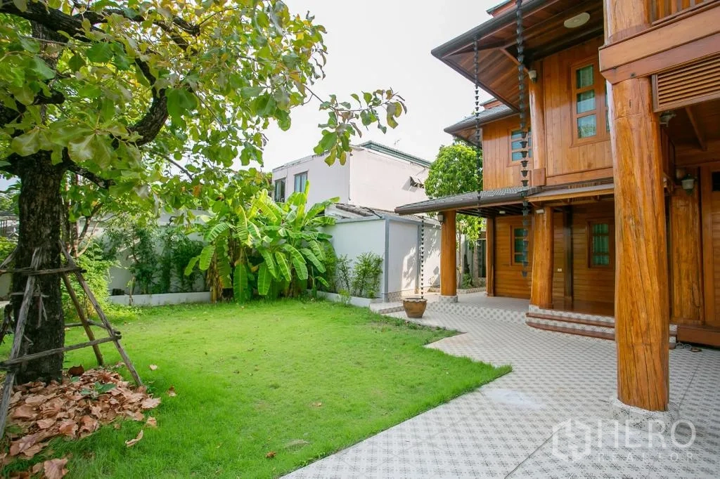 独栋房屋 for rent or sale in Huai Khwang, Bangkok - 后院草坪阴凉，旁有芭蕉与木屋外立面。
