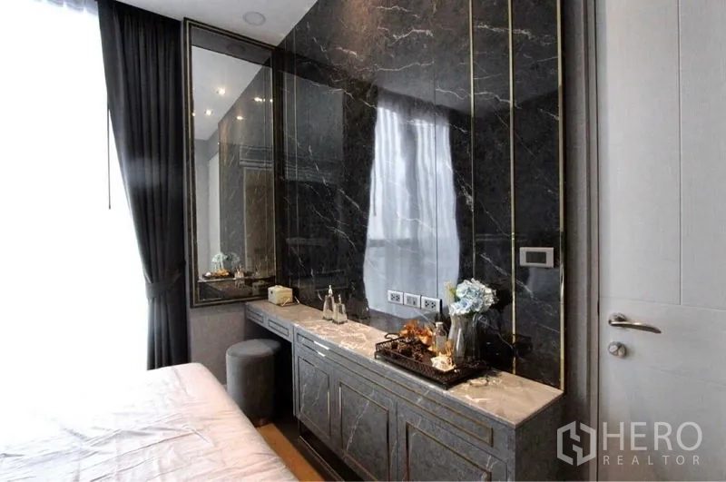 Condominium for rent in Bangkok - Built-in dressing area with black marble feature wall and storage cabinets in the bedroom.