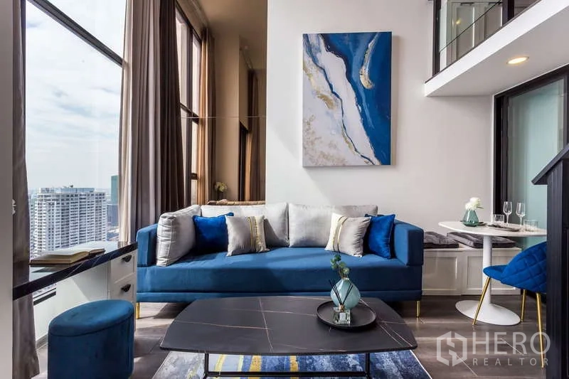 Condominium for rent - Stylish living area with blue couch, loft mezzanine, and contemporary wall art.