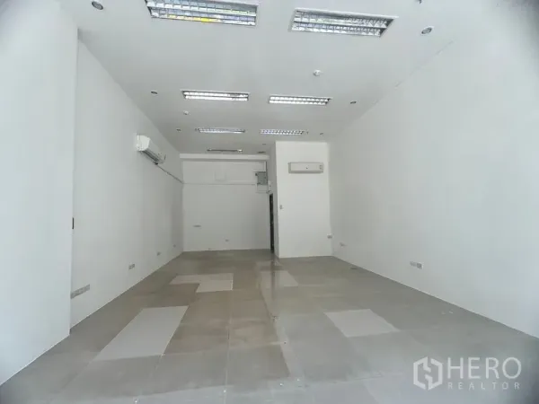 Retail Space for rent in Khlong Toei, Bangkok - Bright white-box retail unit with tiled flooring, recessed fluorescent lighting, and wall-mounted air conditioners.