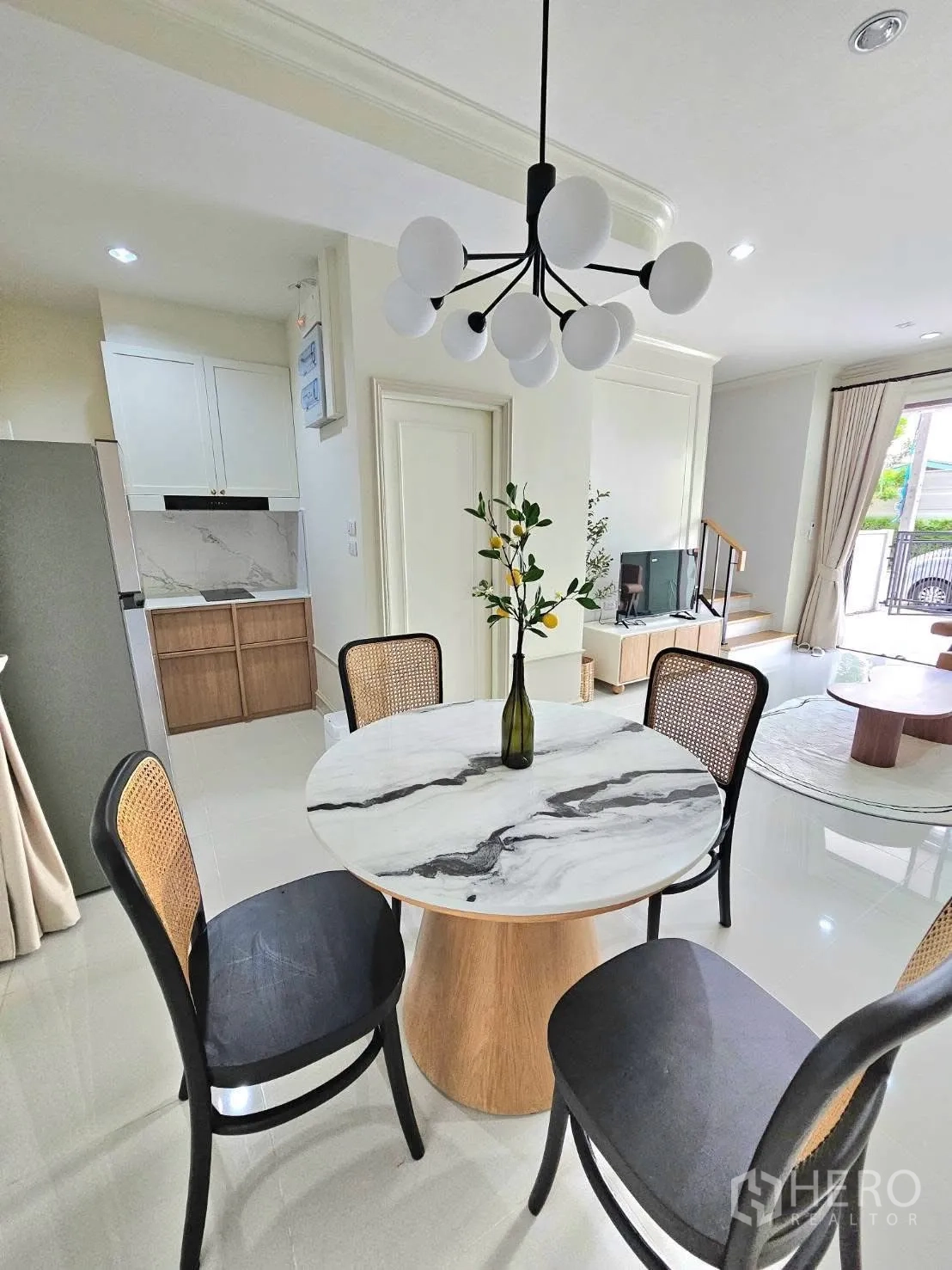 Townhouse for rent in Saphan Sung, Bangkok - Open-plan dining area facing the staircase and TV console, with a black chandelier and large glazed doors.