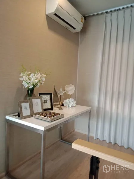Townhouse for rent or sale in Suan Luang, Bangkok - Compact home office nook with air conditioner, white desk and decor next to long curtains.