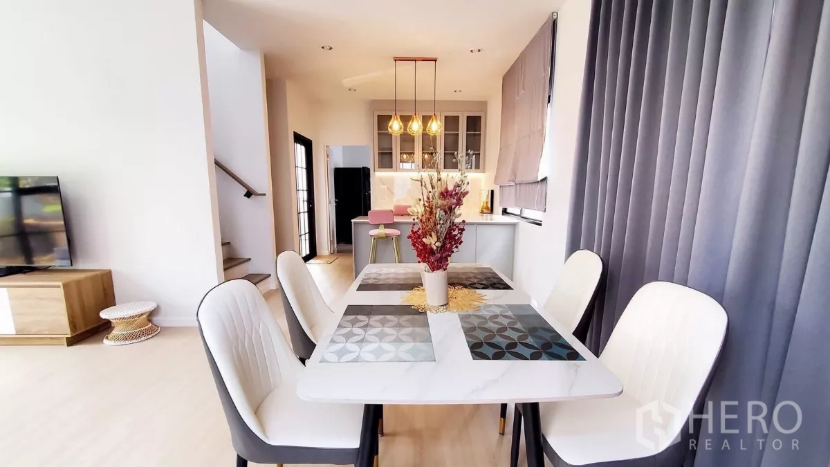 Detached House for rent in Lat Krabang, Bangkok - Four-seat dining table beside a kitchen island with pendant lights and view to the staircase.