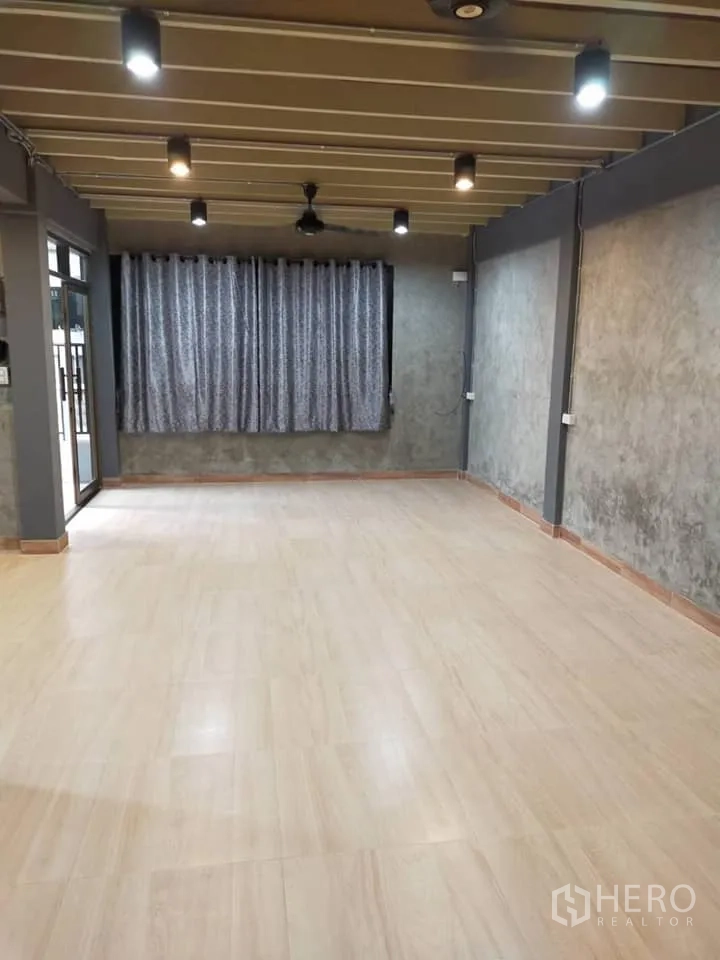 บ้าน ให้เช่าในWatthana, Bangkok - ห้องนั่งเล่นกว้าง พื้นไม้ลามิเนต เพดานคานโชว์พร้อมไฟสปอตไลต์ และหน้าต่างติดผ้าม่าน